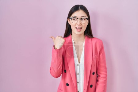 Téléchargez les photos : Chinois affaires jeune femme portant des lunettes souriant avec le visage heureux regardant et pointant vers le côté avec le pouce vers le haut. - en image libre de droit