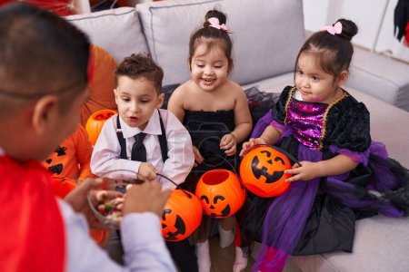 Photo for Hispanic man and group of kids having halloween party distributing sweets at home - Royalty Free Image