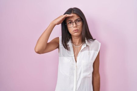 Photo for Brunette young woman standing over pink background wearing glasses worried and stressed about a problem with hand on forehead, nervous and anxious for crisis - Royalty Free Image