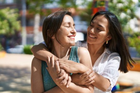 Téléchargez les photos : Two women mother and daughter smiling confident hugging each other at park - en image libre de droit