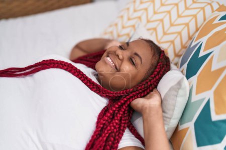 Téléchargez les photos : Femme afro-américaine souriante confiante détendue sur le lit dans la chambre - en image libre de droit