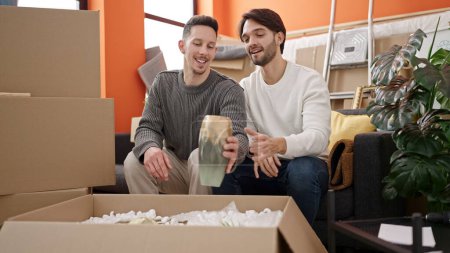 Foto de Dos hombres pareja desembalaje caja de cartón en el nuevo hogar - Imagen libre de derechos
