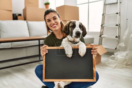 Téléchargez les photos : Jeune femme et chien tenant tableau noir à la maison - en image libre de droit