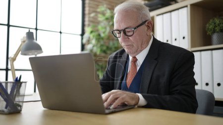 Téléchargez les photos : Travailleur d'affaires senior travaillant avec un ordinateur portable au bureau - en image libre de droit