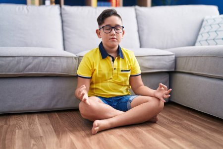 Photo for Adorable hispanic boy doing yoga exercise sitting on floor at home - Royalty Free Image