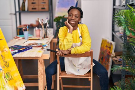 Téléchargez les photos : Artiste afro-américaine souriante confiante au studio d'art - en image libre de droit