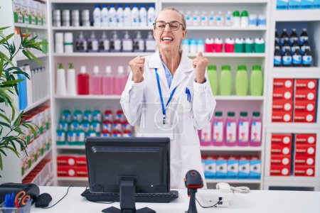 Photo for Young caucasian woman working at pharmacy drugstore excited for success with arms raised and eyes closed celebrating victory smiling. winner concept. - Royalty Free Image