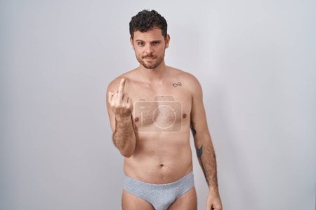 Foto de Young hispanic man standing shirtless wearing underware showing middle finger, impolite and rude fuck off expression - Imagen libre de derechos