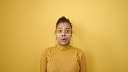 Téléchargez les photos : Jeune femme afro-américaine debout avec expression surprise sur fond jaune isolé - en image libre de droit