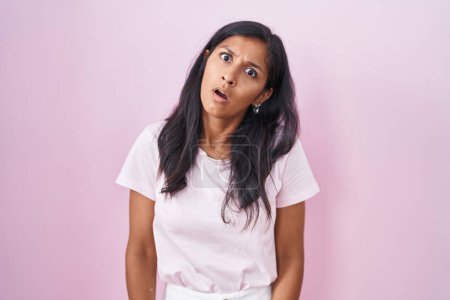 Téléchargez les photos : Jeune femme hispanique debout sur fond rose dans le visage de choc, l'air sceptique et sarcastique, surpris avec la bouche ouverte - en image libre de droit