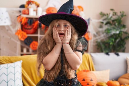 Photo for Adorable blonde girl wearing witch costume with surprise expression at home - Royalty Free Image