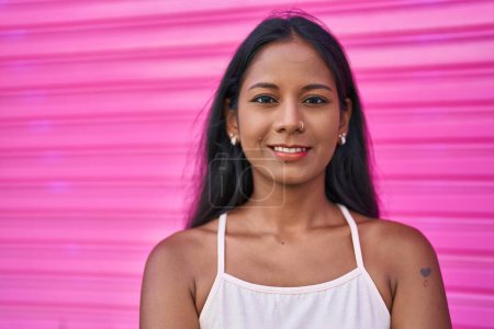 Téléchargez les photos : Jeune belle femme souriante confiante debout sur fond rose isolé - en image libre de droit