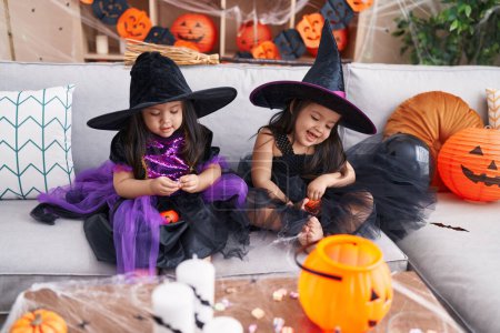 Photo for Adorable twin girls having halloween party holding pumpkin baskets at home - Royalty Free Image