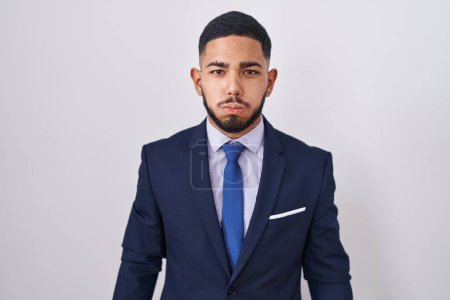 Photo for Young hispanic man wearing business suit and tie puffing cheeks with funny face. mouth inflated with air, crazy expression. - Royalty Free Image