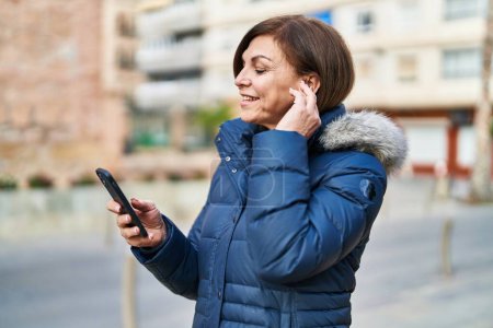 Foto de Mujer de mediana edad hablando en el teléfono inteligente beber café en la calle - Imagen libre de derechos