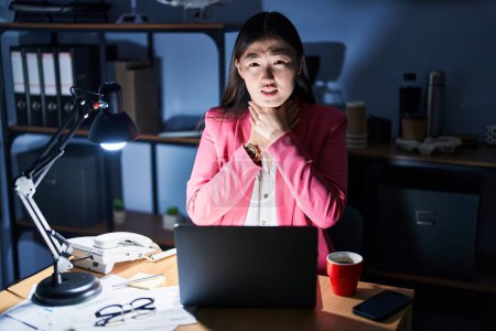 Foto de Mujer joven china que trabaja en la oficina por la noche gritando y sofocar porque estrangulamiento doloroso. problema de salud. concepto de asfixia y suicidio. - Imagen libre de derechos