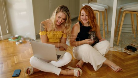 Photo for Two women using laptop sitting on floor with chihuahuas at home - Royalty Free Image
