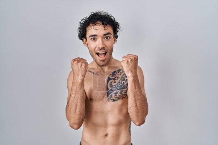 Téléchargez les photos : Homme hispanique debout torse nu célébrant surpris et étonné pour le succès avec les bras levés et les yeux ouverts. concept gagnant. - en image libre de droit