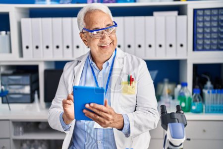 Téléchargez les photos : Homme scientifique senior utilisant pavé tactile travaillant au laboratoire - en image libre de droit