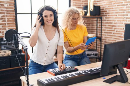 Photo for Two women musicians composing song using keyboard and touchpad at music studio - Royalty Free Image