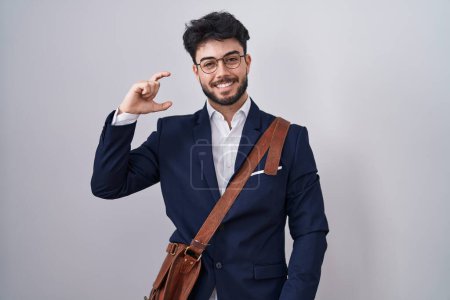Téléchargez les photos : Homme hispanique avec barbe portant des vêtements de travail sourire et geste confiant avec la main faisant signe de petite taille avec les doigts à la recherche et la caméra. concept de mesure. - en image libre de droit