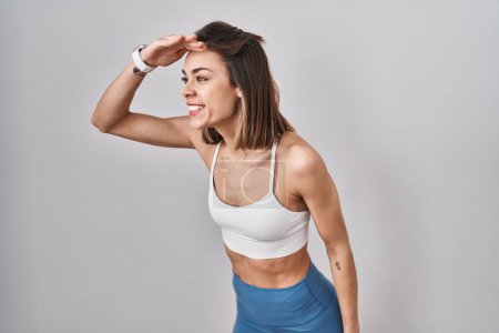 Photo for Hispanic woman wearing sportswear over isolated background very happy and smiling looking far away with hand over head. searching concept. - Royalty Free Image