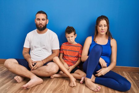 Photo for Family of three sitting on the floor at home depressed and worry for distress, crying angry and afraid. sad expression. - Royalty Free Image