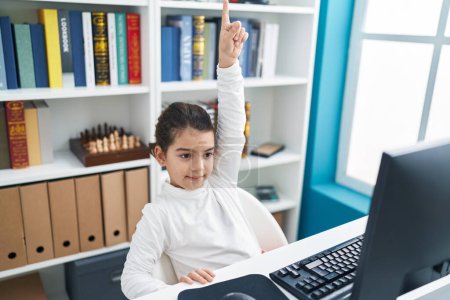 Foto de Adorable estudiante hispana usando computadora con el dedo levantado en el aula - Imagen libre de derechos