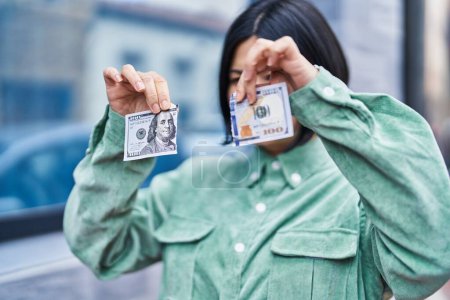 Téléchargez les photos : Young chinese woman breaking 100 dollars banknote at street - en image libre de droit