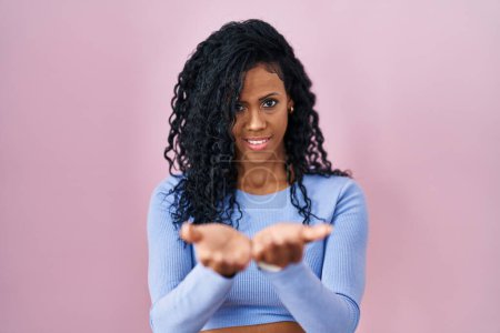 Photo for Middle age hispanic woman standing over pink background smiling with hands palms together receiving or giving gesture. hold and protection - Royalty Free Image