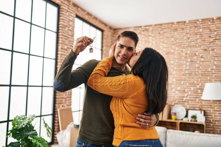 Foto de Hombre y mujer pareja besándose abrazándose uno al otro sosteniendo la llave de la nueva casa en el nuevo hogar - Imagen libre de derechos