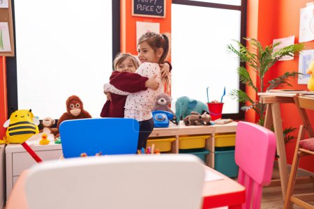 Photo for Adorable girls hugging each other standing at kindergarten - Royalty Free Image