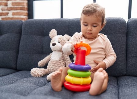 Photo for Adorable hispanic baby playing with hoops game sitting on sofa at home - Royalty Free Image