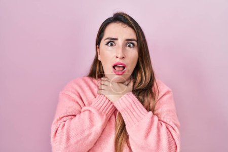 Photo for Young hispanic woman standing over pink background shouting suffocate because painful strangle. health problem. asphyxiate and suicide concept. - Royalty Free Image