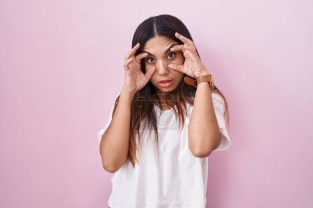 Téléchargez les photos : Jeune femme arabe debout sur fond rose essayant d'ouvrir les yeux avec les doigts, somnolent et fatigué pour la fatigue matinale - en image libre de droit
