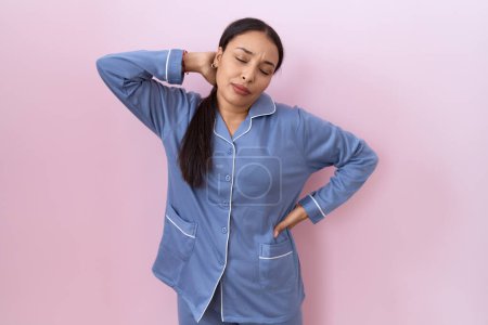 Photo for Young arab woman wearing blue pajama suffering of neck ache injury, touching neck with hand, muscular pain - Royalty Free Image
