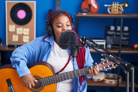 Téléchargez les photos : Femme musicienne afro-américaine chantant une chanson jouant de la guitare classique au studio de musique - en image libre de droit