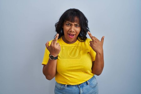 Foto de Hispanic woman standing over blue background showing middle finger doing fuck you bad expression, provocation and rude attitude. screaming excited - Imagen libre de derechos