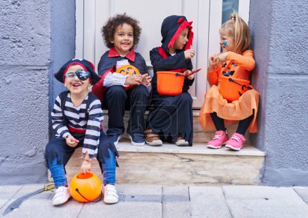 Foto de Grupo de niños con disfraz de halloween sosteniendo cesta de calabaza en la calle - Imagen libre de derechos