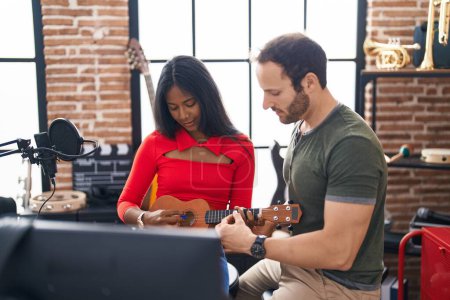 Téléchargez les photos : Man and woman musicians playing ukulele at music studio - en image libre de droit