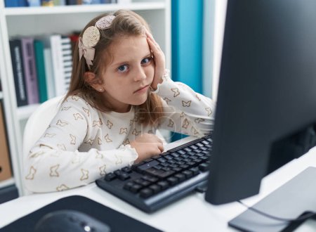 Téléchargez les photos : Adorable fille blonde étudiante fatiguée à l'aide de l'ordinateur en classe - en image libre de droit