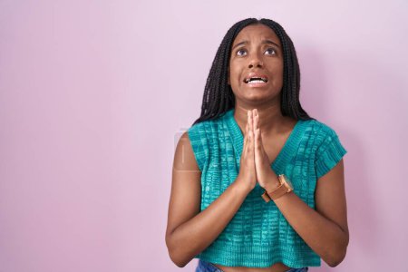 Photo for Young african american with braids standing over pink background begging and praying with hands together with hope expression on face very emotional and worried. begging. - Royalty Free Image