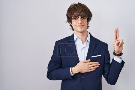 Photo for Hispanic business young man wearing glasses smiling swearing with hand on chest and fingers up, making a loyalty promise oath - Royalty Free Image