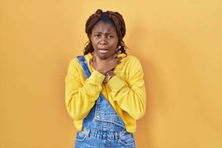 Téléchargez les photos : Femme africaine debout sur fond jaune criant suffoquer parce étranglement douloureux. problème de santé. concept d'asphyxie et de suicide. - en image libre de droit