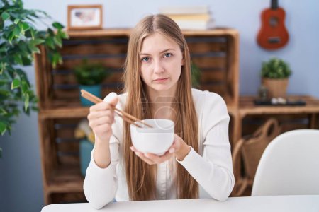 Photo for Young caucasian woman eating asian food using chopsticks depressed and worry for distress, crying angry and afraid. sad expression. - Royalty Free Image