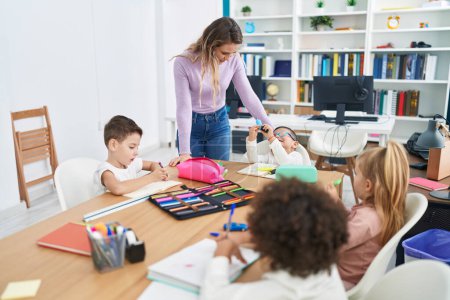 Photo for Woman and group of kids having lesson sitting on table at classroom - Royalty Free Image