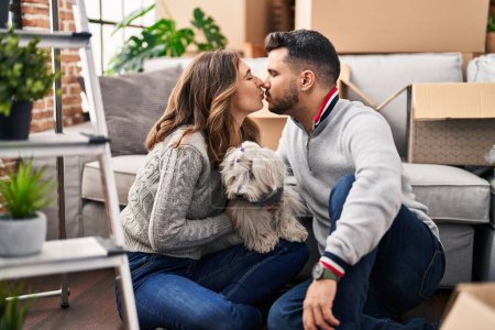 Téléchargez les photos : Homme et femme assis sur le sol avec chien embrassant à la nouvelle maison - en image libre de droit