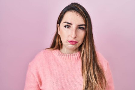 Photo for Young hispanic woman standing over pink background relaxed with serious expression on face. simple and natural looking at the camera. - Royalty Free Image