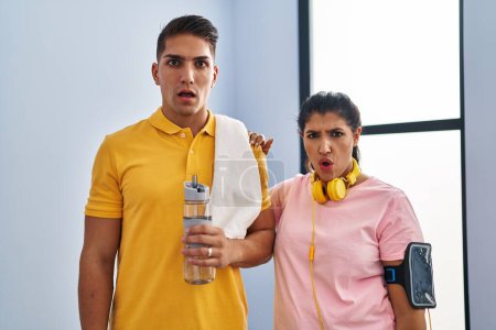Photo for Young couple wearing sportswear and headphones scared and amazed with open mouth for surprise, disbelief face - Royalty Free Image