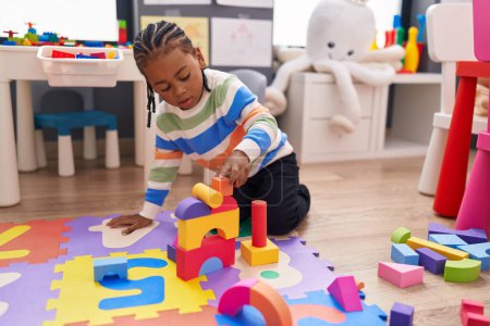 Photo for African american boy playing with construction blocks sitting on floor at kindergarten - Royalty Free Image